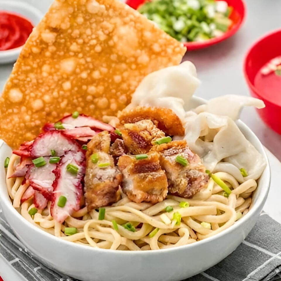 Indonesian noodles with sliced red pork, crispy pork belly, dumplings, and a fried wonton.
