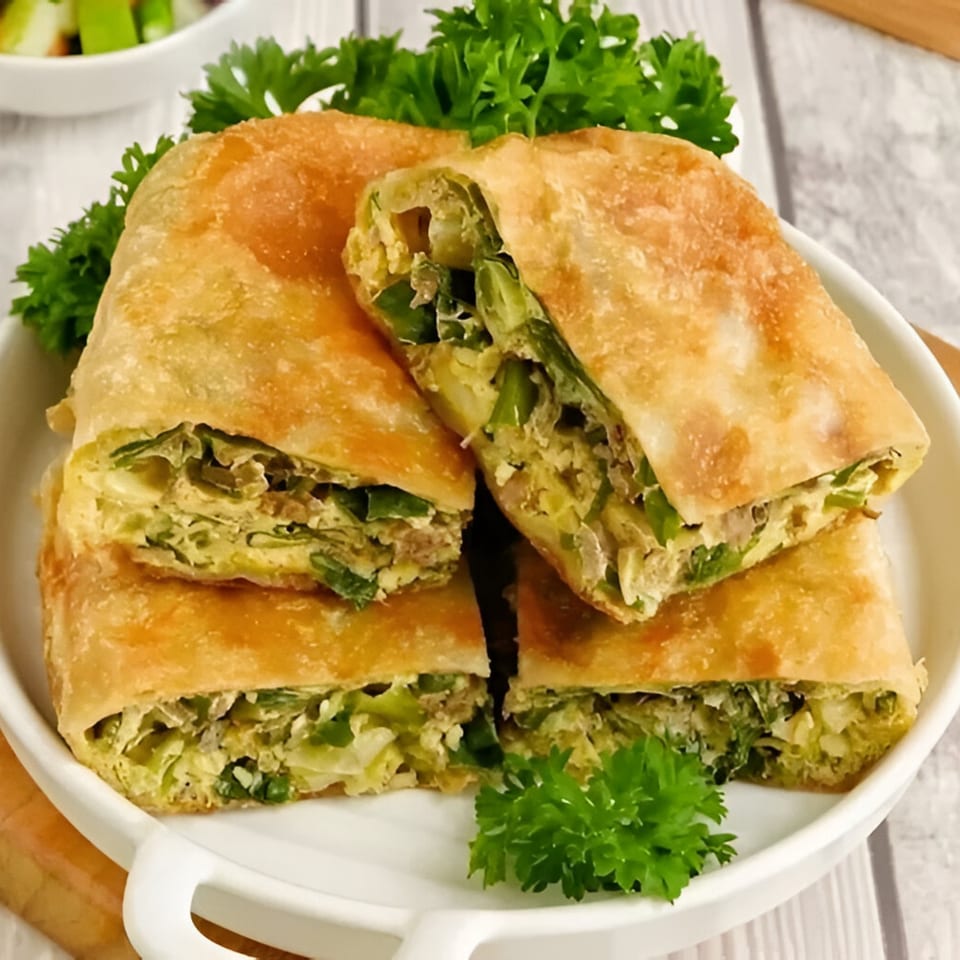 Four pieces of golden-brown Indonesian Martabak, filled with egg and green vegetables, garnished with parsley.