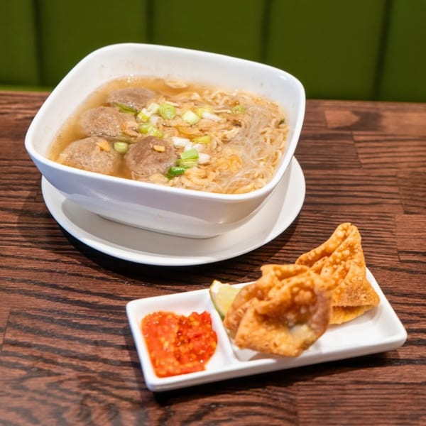 Indonesian meatball soup with noodles, green onions, and fried wontons with chili sauce.